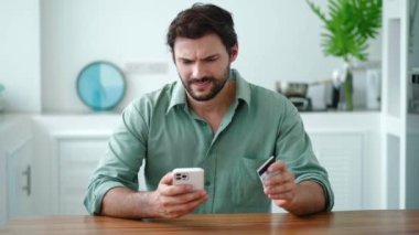 Çekici İspanyol adam telefon kullanıyor, para transfer ediyor. Bozuk para eksikliği yüzünden faturayı ödeyemediği için kredi kartını masaya fırlatıyor.