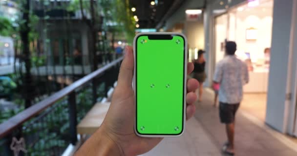 男性の手はプロモーションプレゼンテーションのためのコピー広告スペース緑のクロマキー画面と垂直方向に携帯電話を保持しています モックアップ — ストック動画