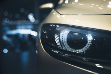 Siyah arkaplan üzerine mavi modern arabanın ksenon ışığıyla yakın çekim ön far ve kopyalama alanı