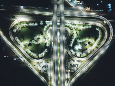 Gece ışığında yeşil egzersiz arka planına sahip kentsel karayolu kavşağının hava görüntüsü.