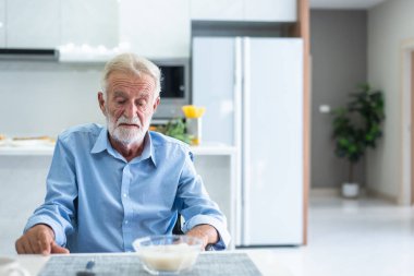 An elderly man has anorexia. Can't eat rice in the morning of the day clipart