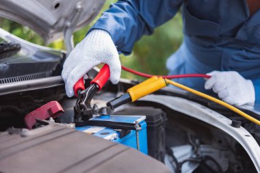 Aktülatör şarj oluyor. Eller ve terminaller. Araba tamiri. Benzin istasyonu, arabanın aküsünü elektrik kablosuyla şarj et..