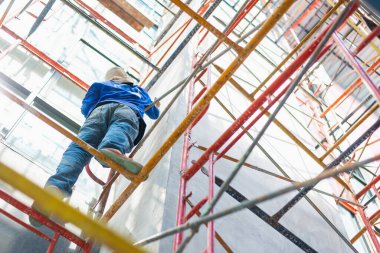 İnşaat işçisi inşaat sahasına güvenlik ekipmanları olmadan tırmanıyor..