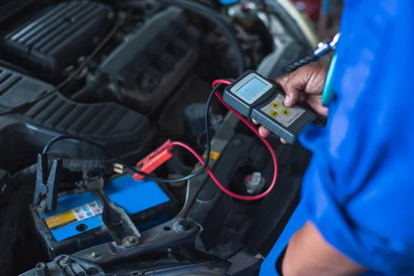 汽车机械师用万用表电压表测量汽车电池的电压 — 图库照片