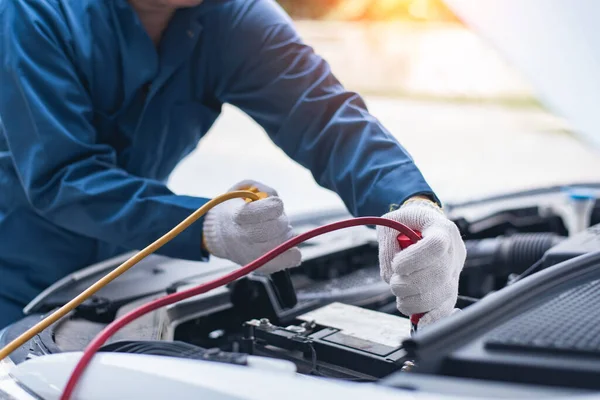 Battery charging. Terminals and hands. auto repair a gas station, hand up close using jumper wires to electrically charge a car battery.