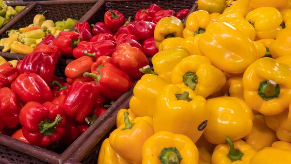 Tezgahtaki bir kutuda kırmızı ve sarı biberler. Süpermarkette sebze reyonu.