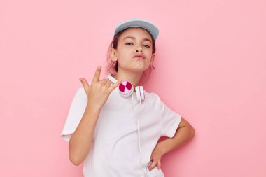 Beyaz tişörtlü güzel bir genç kız kulaklığı ve değişmemiş bir şapka çocukluğu.