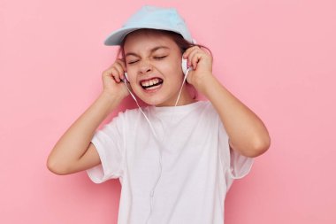 Beyaz tişörtlü, pembe şapkalı tatlı kız kulaklıkları.