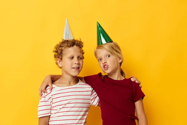 Portrét roztomilých dětí v neformálním oblečení s čepicemi na hlavě na barevném pozadí — Stock fotografie