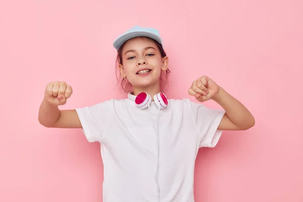 Auriculares de niña pequeña en una camiseta blanca y una niñez gorra inalterada — Foto de Stock