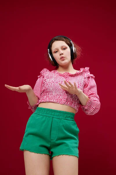 Mulher bonita em blusa rosa e shorts verdes com fones de ouvido ouvindo música — Fotografia de Stock