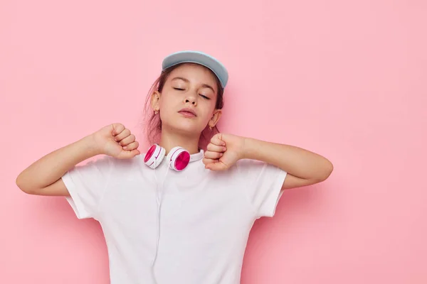 Ακουστικά κοριτσάκι σε ένα λευκό t-shirt και ένα καπέλο παιδική ηλικία αναλλοίωτη — Φωτογραφία Αρχείου