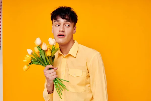 Красивий хлопець в жовтих окулярах з букетом квітів жовтий фон незмінний — стокове фото