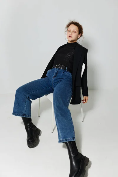 검은 재킷을 입고 의자에 앉아 변경되지 않은 라이프 스타일 포즈를 취하는 젊은 여성의 사진 — 스톡 사진