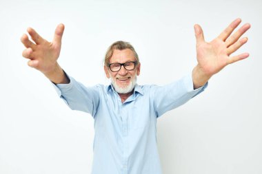 Mavi gömlekli emekli yaşlı bir adamın el hareketleriyle çekilmiş fotoğrafı.