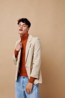 Elinde telefonuyla poz veren genç bir adam zarif bir ceketle hayat tarzını değiştirmemiş.