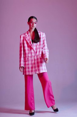 Güzel, genç bir kadının portresi. Lüks kıyafetler. Ekose ceket, pembe arka plan değiştirilmemiş.