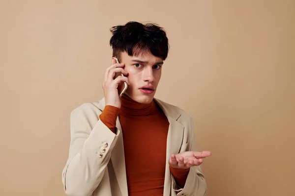Retrato de un joven teléfono móvil en las manos de la comunicación en un traje de luz de fondo inalterado — Foto de Stock