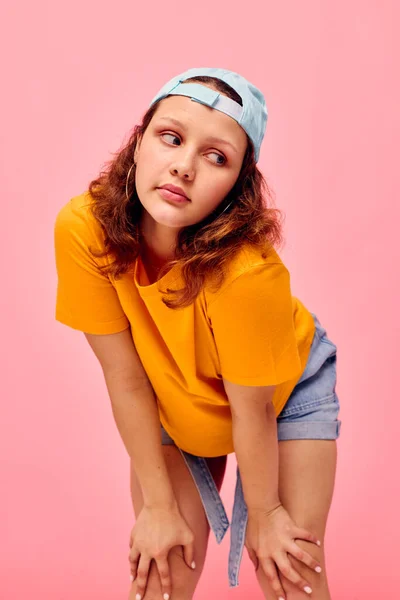 Beautiful woman in a yellow t-shirt and blue cap posing emotions pink background unaltered — Fotografia de Stock