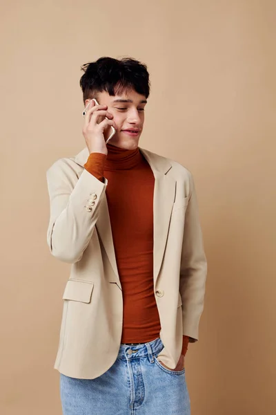 Foto ung pojkvän mobiltelefon i händerna på kommunikation i en kostym mode ljus bakgrund oförändrad — Stockfoto