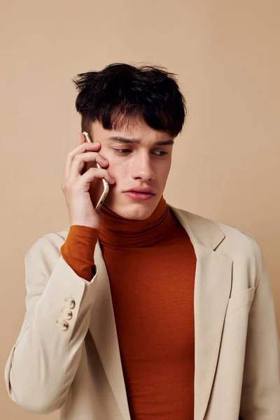 Un joven posando con un teléfono en sus manos en una chaqueta elegante modelo de estudio — Foto de Stock