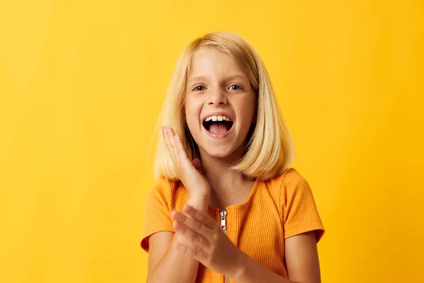 Cute little girl with blond hair posing yellow background — Stock fotografie