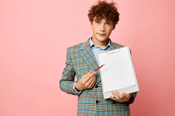 Young curly-haired man in a plaid jacket copy-space folder pink background unaltered — Fotografia de Stock