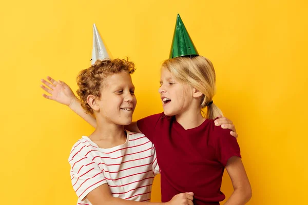 Μικρά παιδιά διακοπές διασκέδαση με καπάκια στο κεφάλι σας κίτρινο φόντο — Φωτογραφία Αρχείου