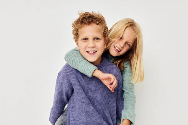 Boy and girl in multi-colored sweaters posing for fun light background — Stock fotografie