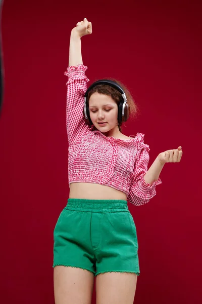 Όμορφο κορίτσι με πράσινο σορτς κινείται σε ακουστικά ακούγοντας μουσική — Φωτογραφία Αρχείου