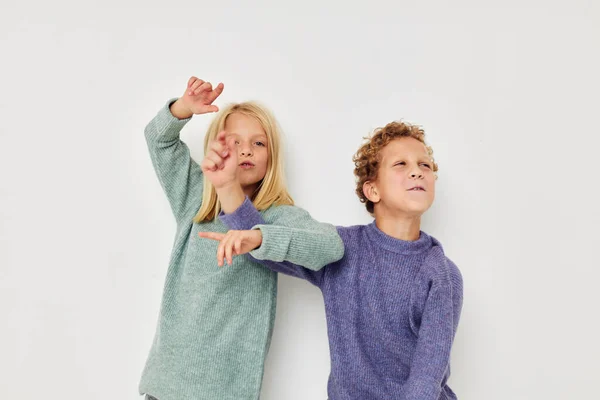 Roztomilé stylové děti v multi-barevné svetry pózují pro zábavu světlé pozadí — Stock fotografie