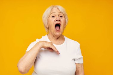 Beyaz tişörtlü, eski dost canlısı bir kadının portresi. Eğlenceli, yakın çekim duyguları sergiliyor.