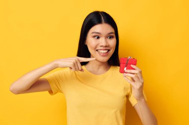 Sarı tişörtlü Asyalı kadın bayram hediyesi duyguları sarı arka plan değiştirilmemiş.