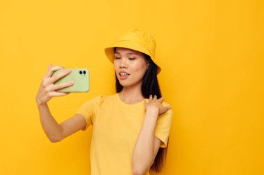 Sarı şapkalı ve tişörtlü güzel bir esmer telefon stüdyosu modelinde değişmeden konuşuyor.