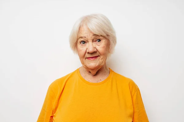 Smiling elderly woman in casual t-shirt gestures with his hands isolated background — Foto de Stock