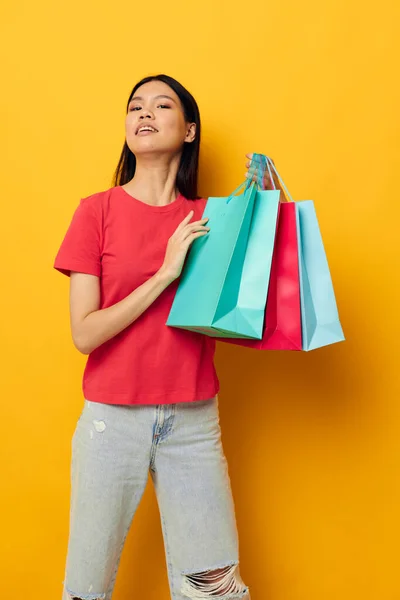 Woman with Asian appearance shopping bags in red t-shirt isolated background unaltered — Stockfoto