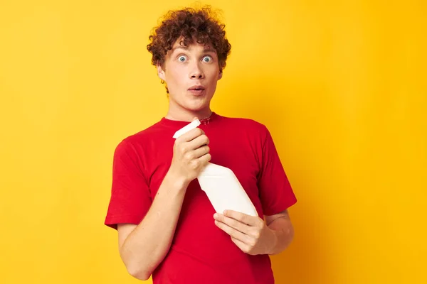 Young curly-haired man in a red t-shirt detergents in hands posing Lifestyle unaltered — 图库照片