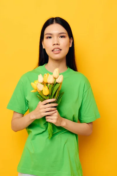 Жінка зелена футболка букет жовтих квітів жовтий фон незмінний — стокове фото