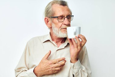 Beyaz arka planı ve beyaz gömleği olan gözlüklü yaşlı bir adam.