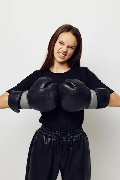 Young woman in boxing gloves punch in black pants and a T-shirt isolated background — 图库照片
