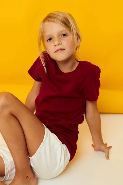 Niña en el suelo posando fondo amarillo — Foto de Stock