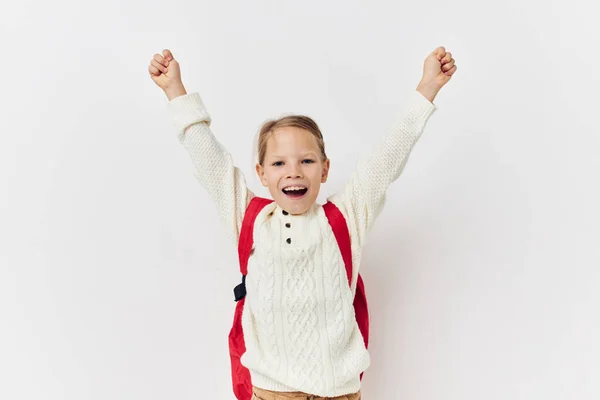 Klein meisje school rugzak met een hoed op zijn hoofd licht achtergrond — Stockfoto