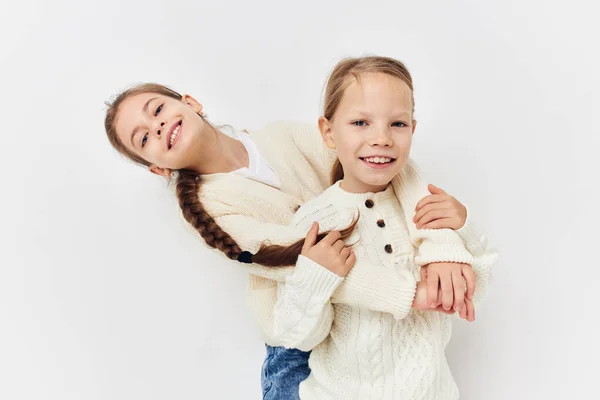 Two little girls in sweaters posing childhood light background — Stockfoto
