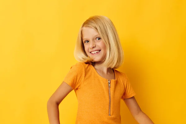 Young blonde girl in a yellow t-shirt smile posing studio childhood lifestyle unaltered — Stockfoto