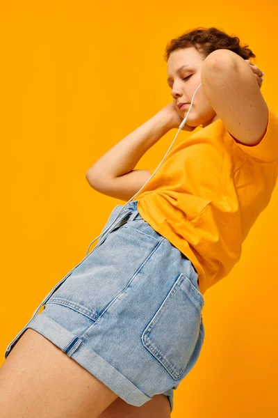 Mulher bonita amarelo t-shirt fones de ouvido entretenimento música divertida amarelo fundo inalterado — Fotografia de Stock