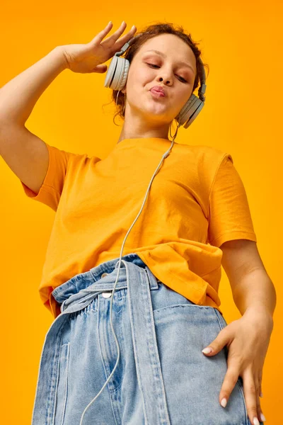 Pretty woman grimace headphones music technology yellow background unaltered — Stockfoto