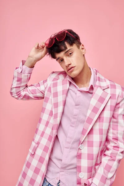 Ένας νεαρός άνδρας ροζ γυαλιά καρό σακάκι μόδας ποζάρουν ροζ φόντο αμετάβλητη — Φωτογραφία Αρχείου