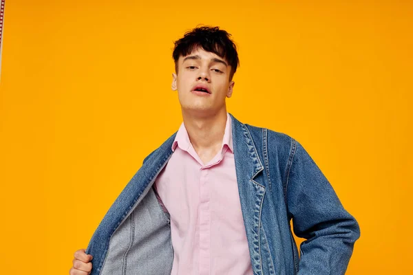 Hombre guapo en chaqueta de mezclilla estilo joven posando fondo amarillo — Foto de Stock