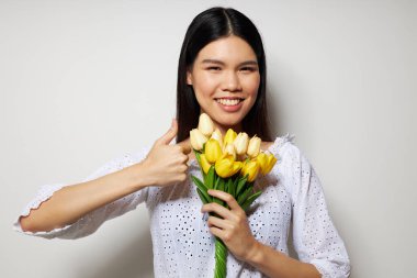 Asyalı görünümlü bir kadın. Romantik çiçek buketi. Stüdyo modelinin yanında.