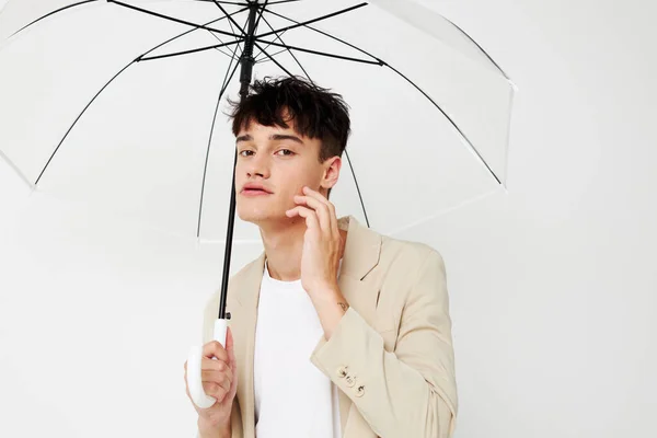 Nice young guy with an open umbrella in a suit light background — ストック写真
